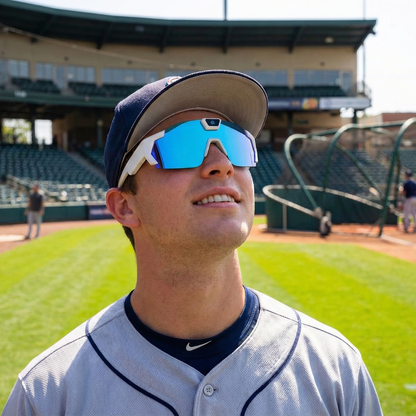 Person wearing a baseball cap and sunglasses on a baseball field