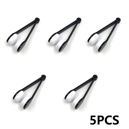 Set of five black tongs with white silicone tips on a white background